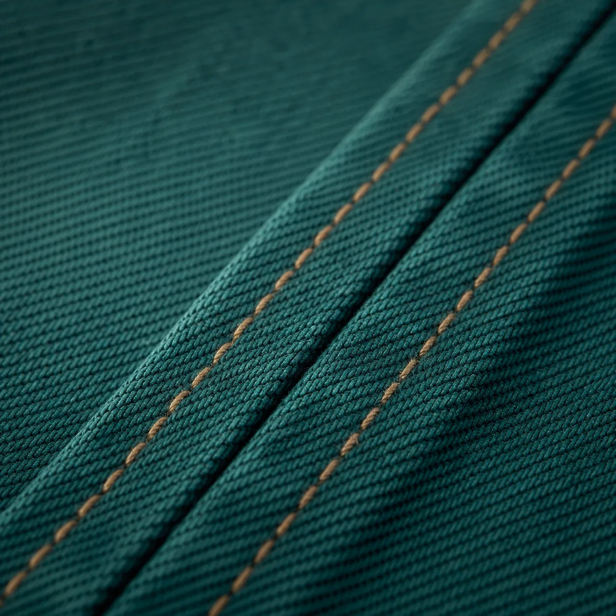 Macro of a flat-felled seam with even double topstitching running through heavy twill.